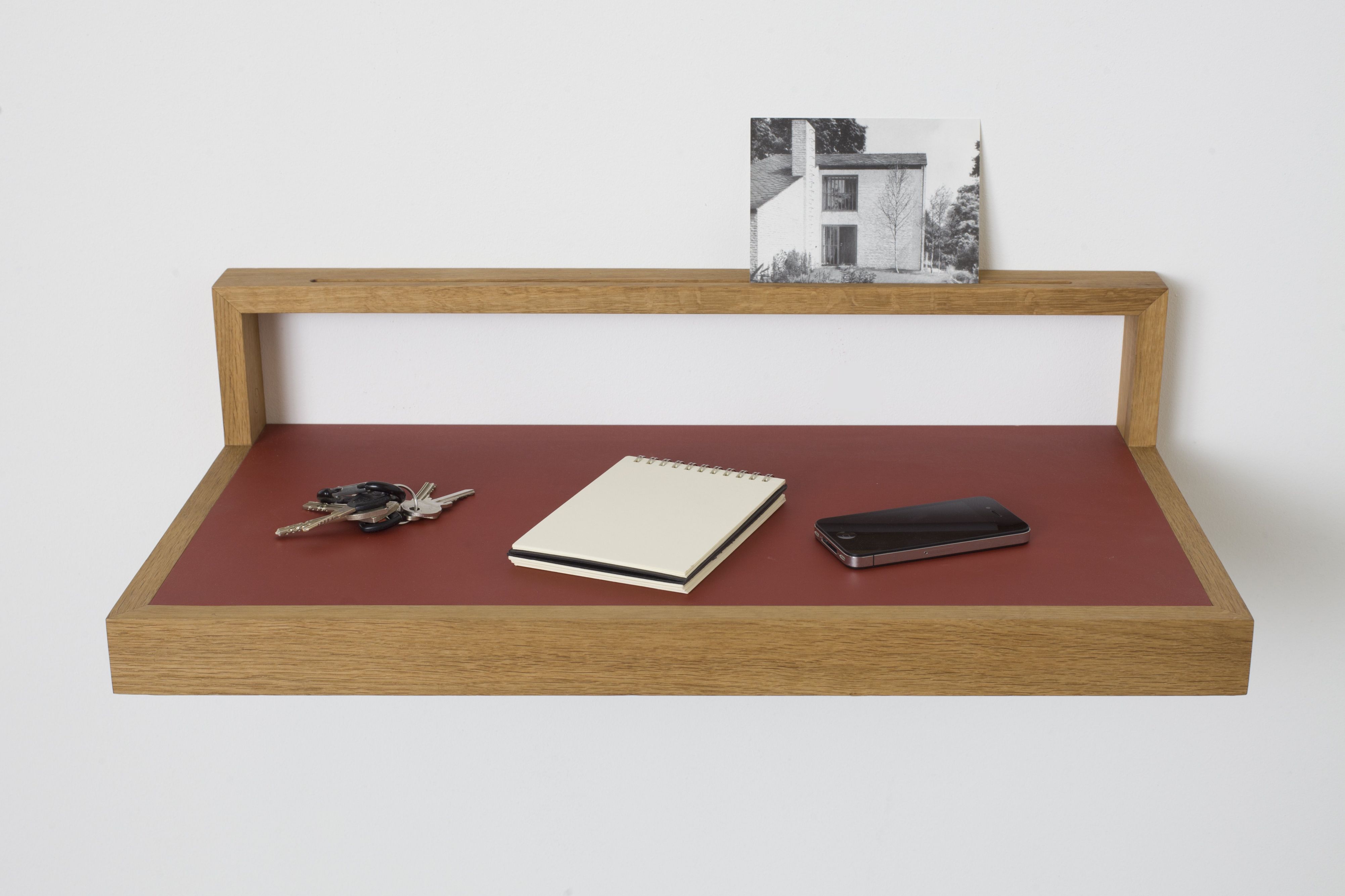 Ablageboard "buck" aus Holz mit Schlüssel, Notizblock und Smartphone auf roter Ablagefläche.