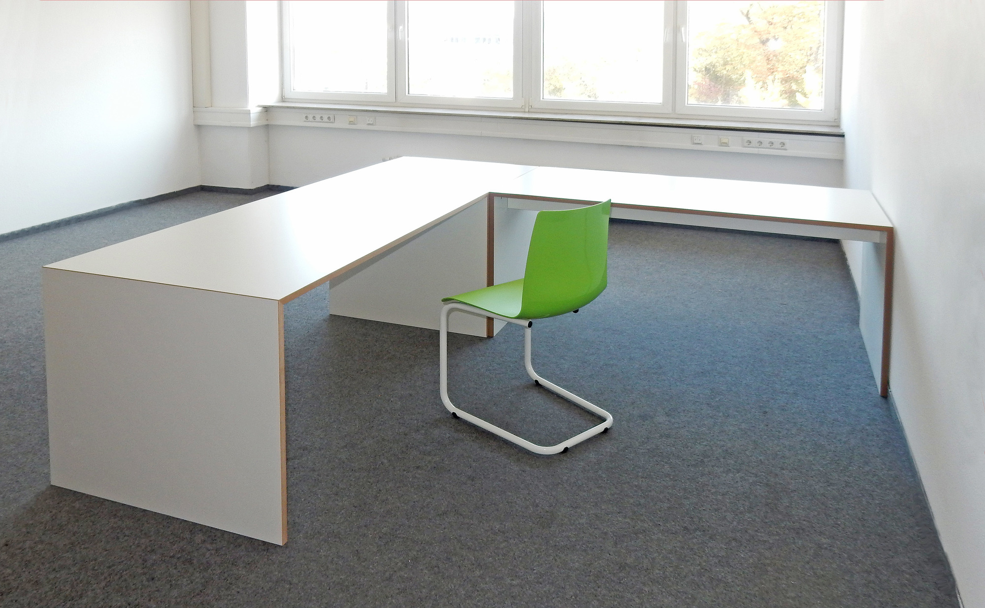 Großer, weißer Freistell Tisch von Tojo mit einem grünen Stuhl im modernen Büro.