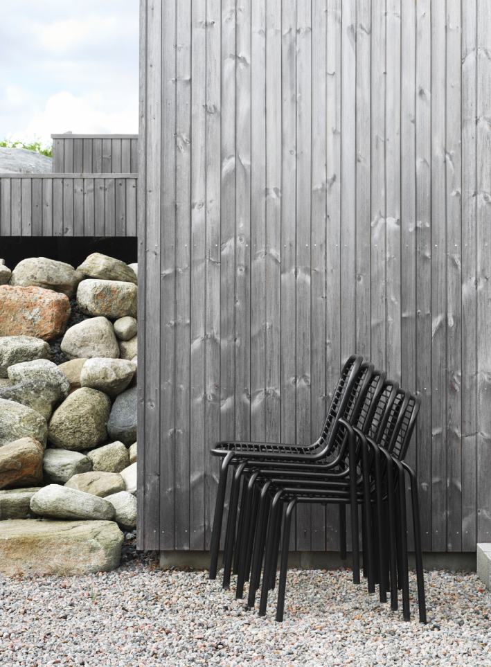 Stapel schwarzer Vig Chair Stühle von Normann Copenhagen für den Außenbereich vor Holzwand.
