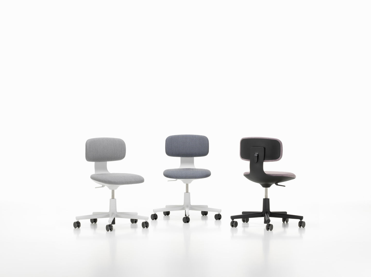 Drei Vitra Rookie Bürodrehstühle in Grau und Schwarz mit Rollen vor einem weißen Hintergrund.