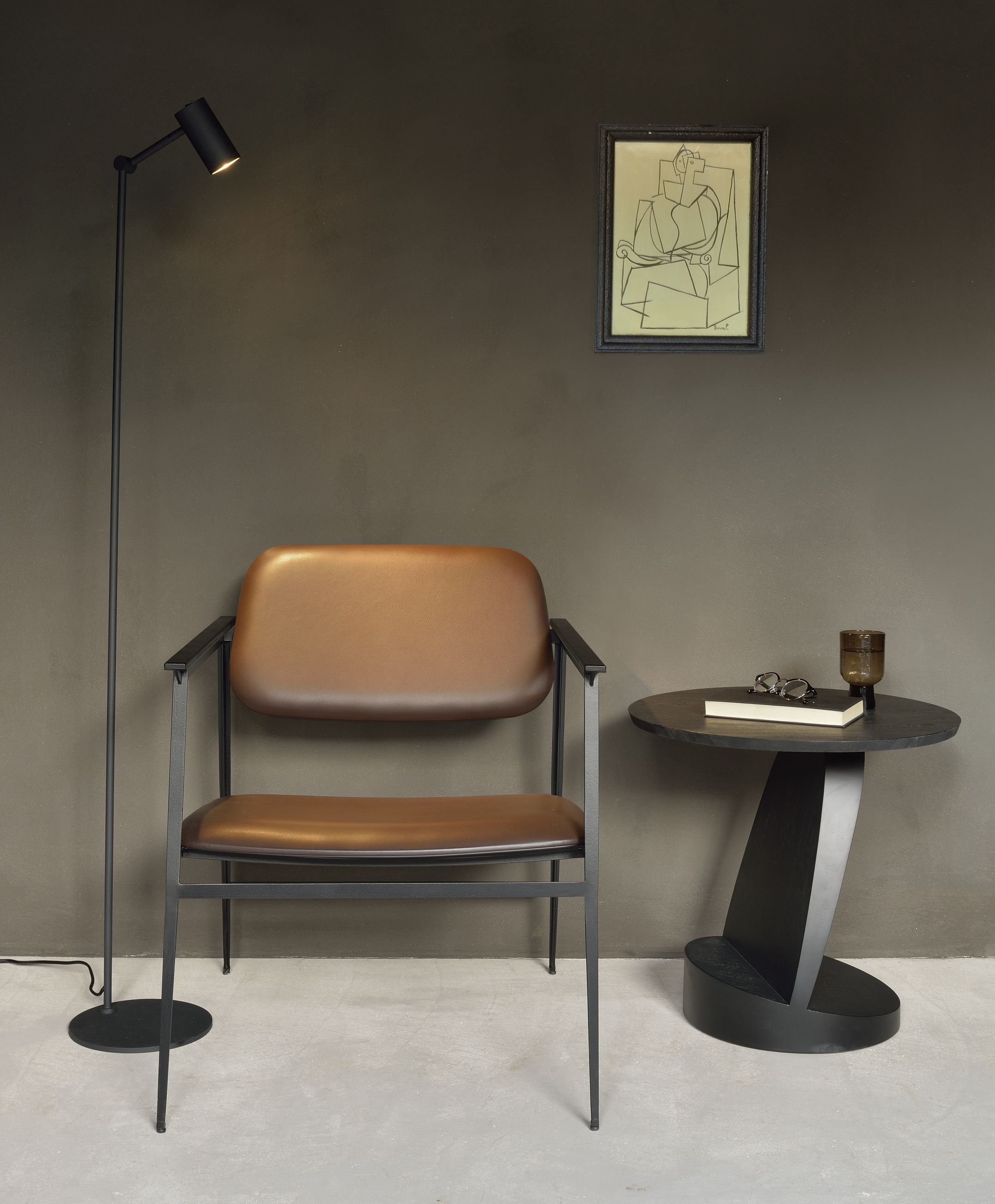 Brauner Ledersessel mit schwarzem Metallgestell, Stehlampe und Beistelltisch im modernen Wohnzimmer.