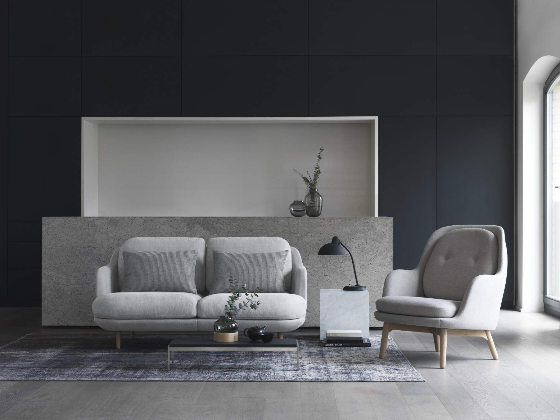 Heller Wohnraum mit Fritz Hansen PK62 Couchtisch, Sofa, Sessel, Lampe und Dekoration auf einem Teppich.