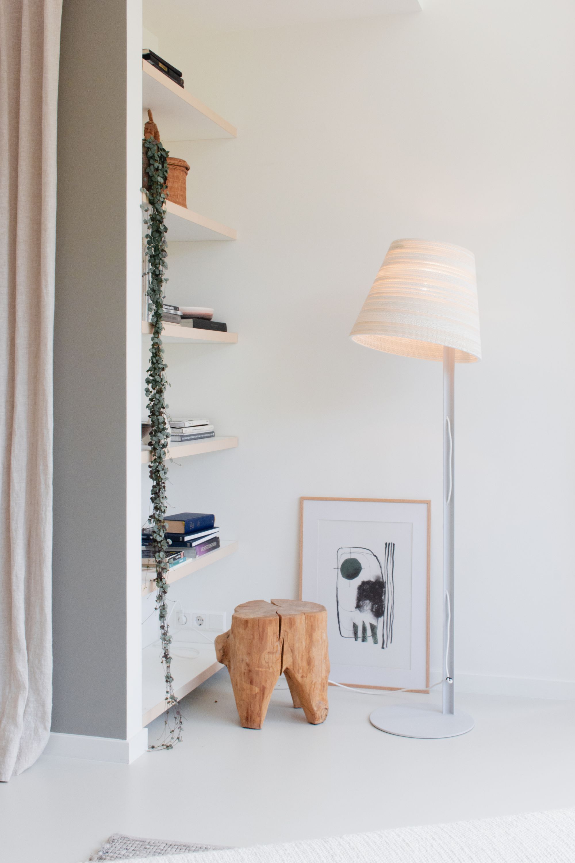 Weiße Tilt Stehleuchte Scraplights von Graypants im modernen Wohnzimmer mit Holzschemel und Regal.