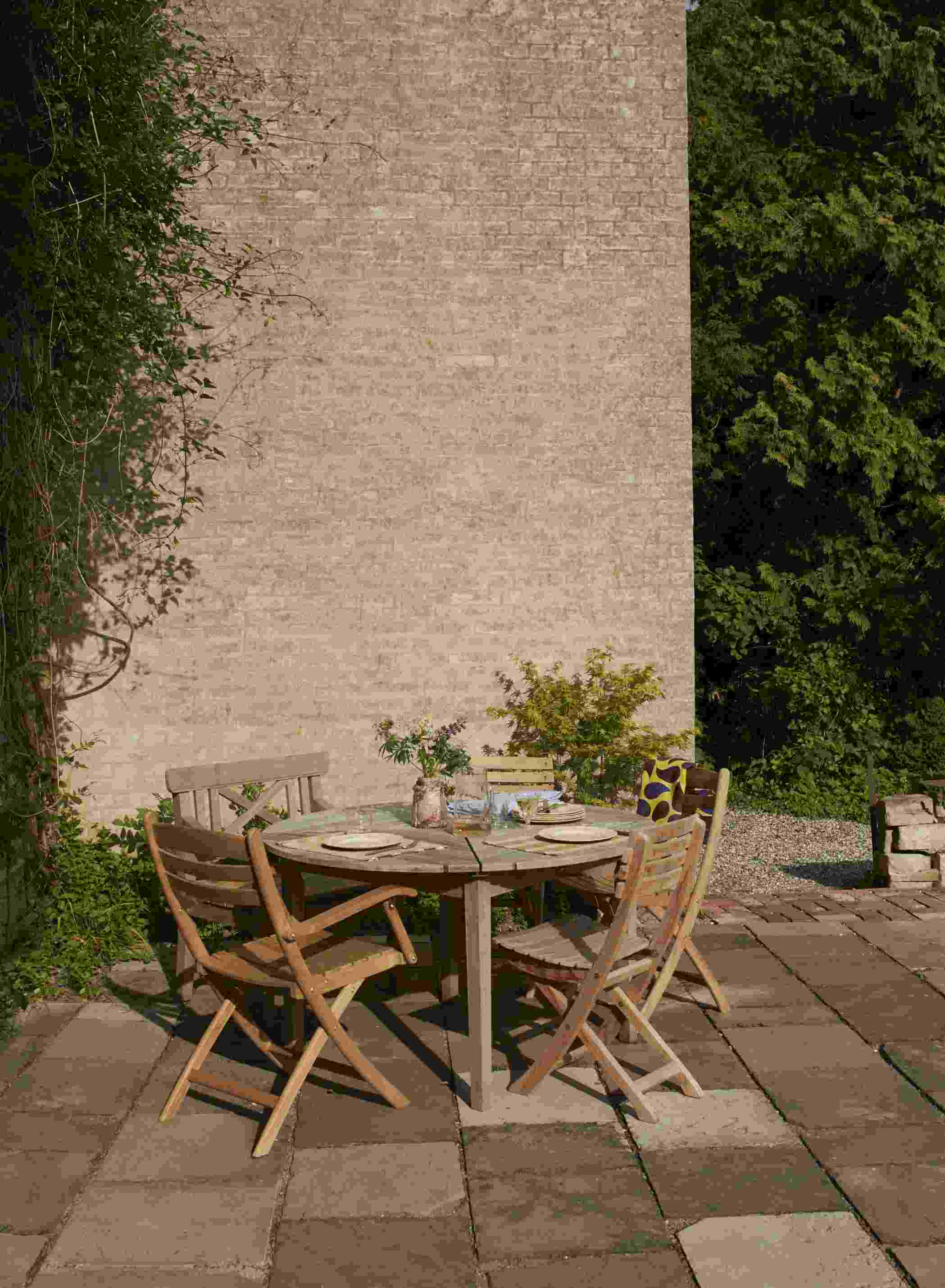 Drachmann Tisch von Skagerak by Fritz Hansen mit Holzstühlen auf einer Terrasse im Garten.