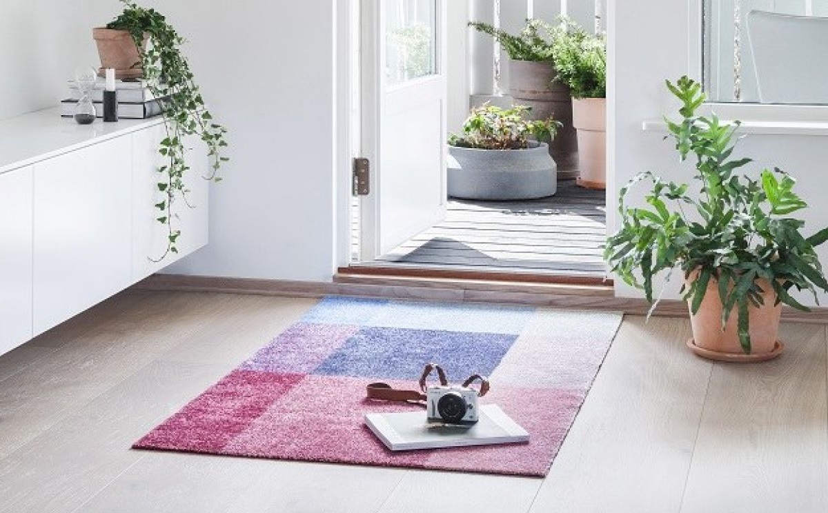 Moderner Teppich mit geometrischem Muster in Rosa und Blau im hellen Eingangsbereich mit Kamera.