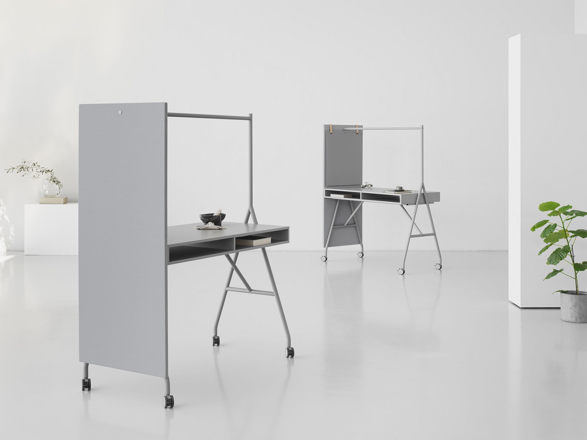 Zwei graue Hangout High Desk Stehtische von Mizetto mit Rollen und Trennwand in einem hellen Raum.