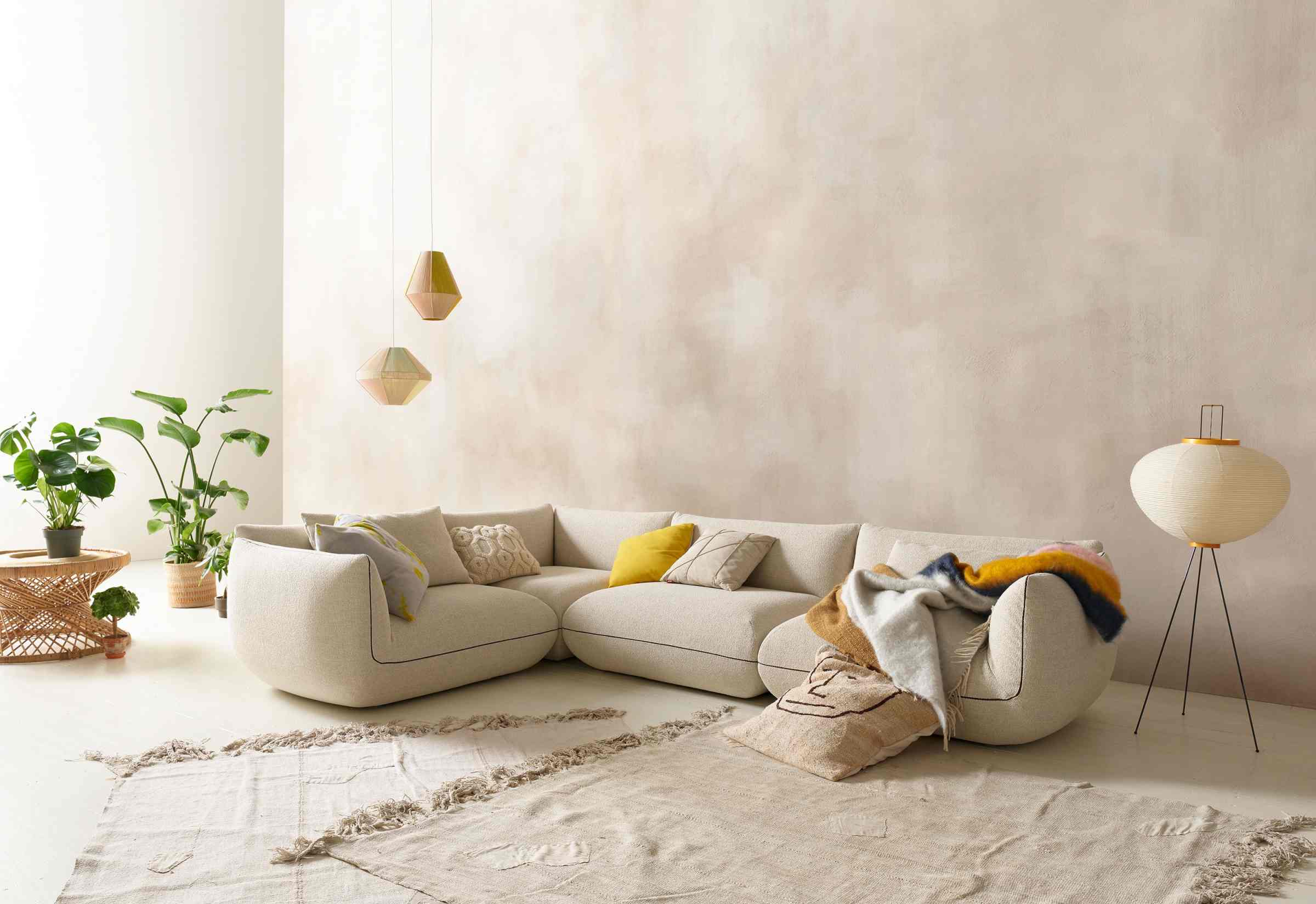 Helles Wohnzimmer mit Jalis21 Modulsofa von Cor, beige, ohne Armlehnen, mit Kissen und Decke.