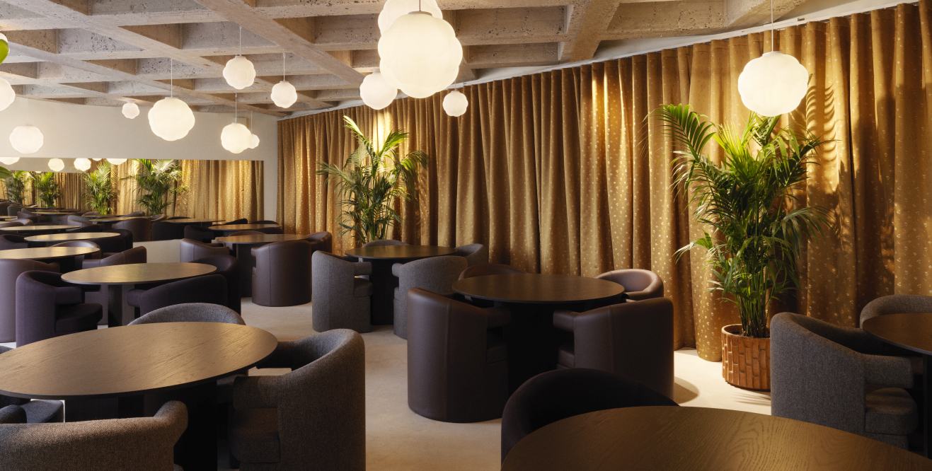 Innenraumansicht eines Restaurants mit mehreren Bubba Pendelleuchten von Normann Copenhagen, die von der Decke hängen.