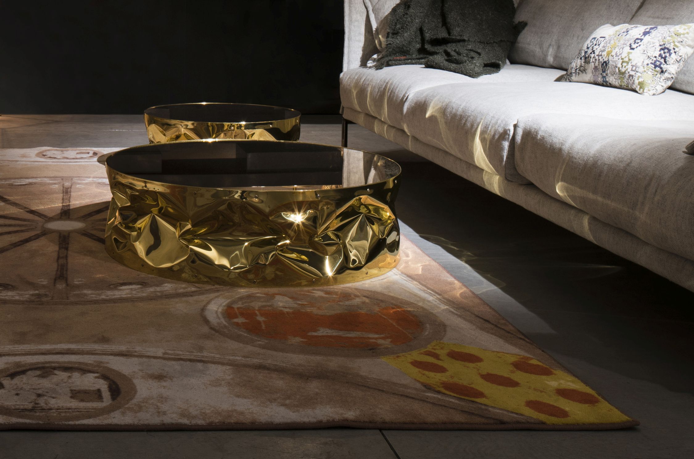 Goldener Tab.ulone Couchtisch von Opinion Ciatti mit schwarzer Tischplatte neben einem Sofa.