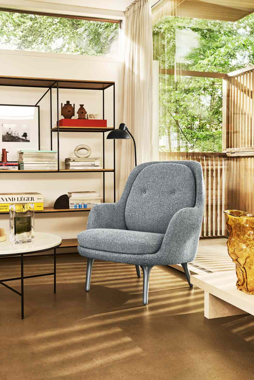 Grauer Fri Sessel von Fritz Hansen im modernen Wohnzimmer mit Bücherregal und Fenster.