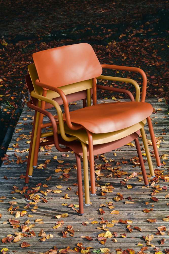 Drei Fermob Studie Lounge Sessel Outdoor in Herbstfarben gestapelt auf einer Holzterrasse mit Laub.