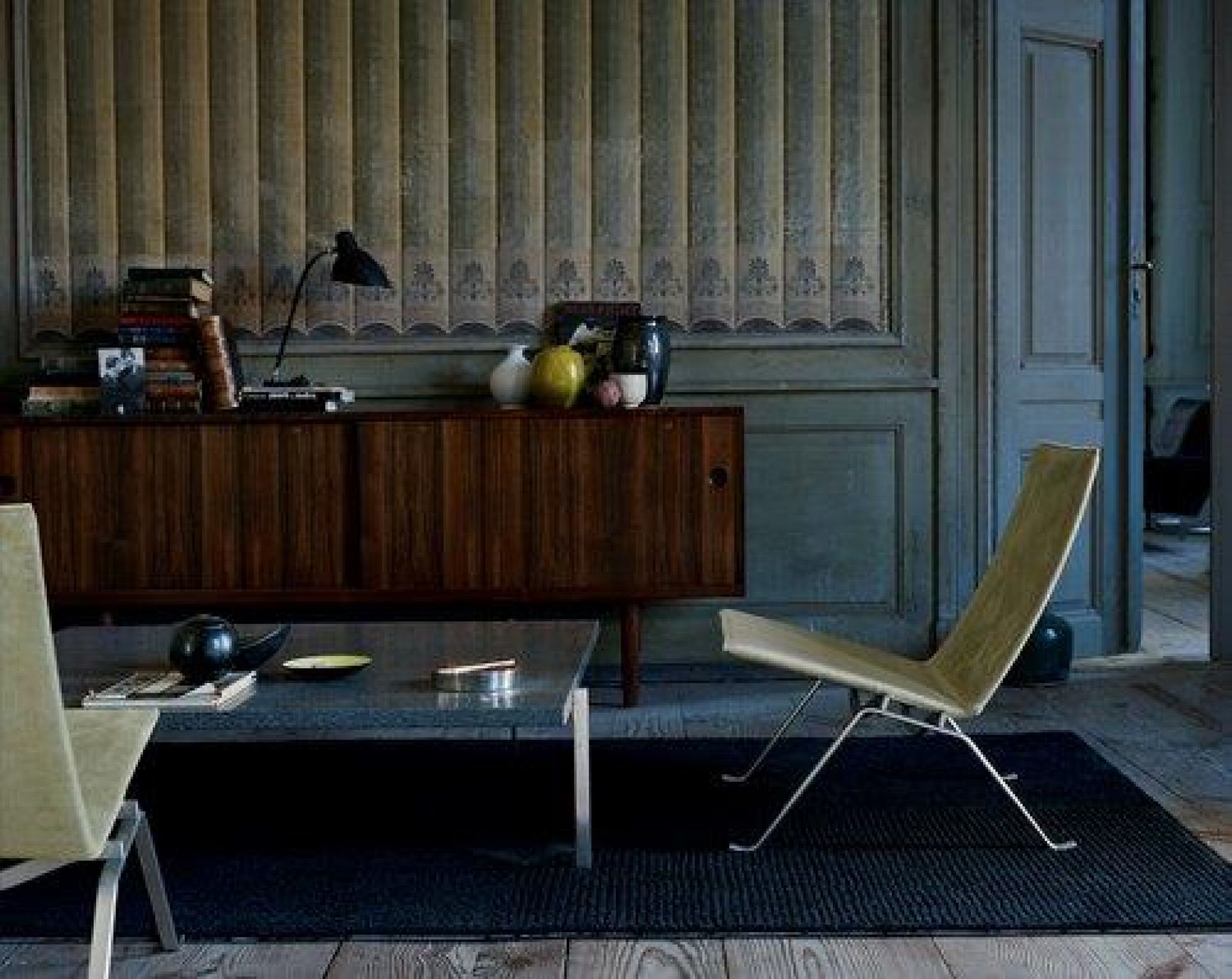 PK22 Sessel von Fritz Hansen in beigem Leder und Stahlgestell vor dunkler Wand.