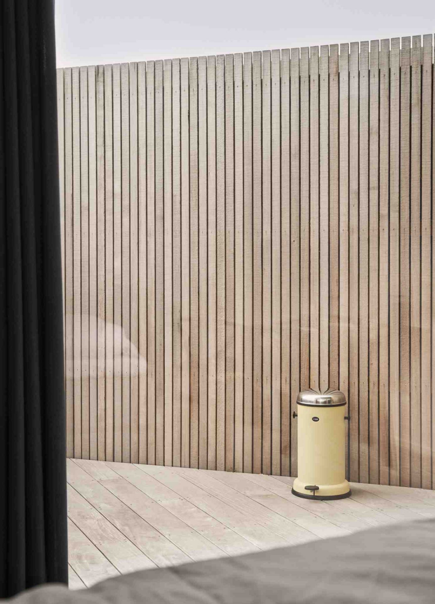 Marie´s Yellow Vipp Treteimer Limited Edition vor einer Holzwand auf einem Holzboden. Design Mülleimer für Bad und Küche.