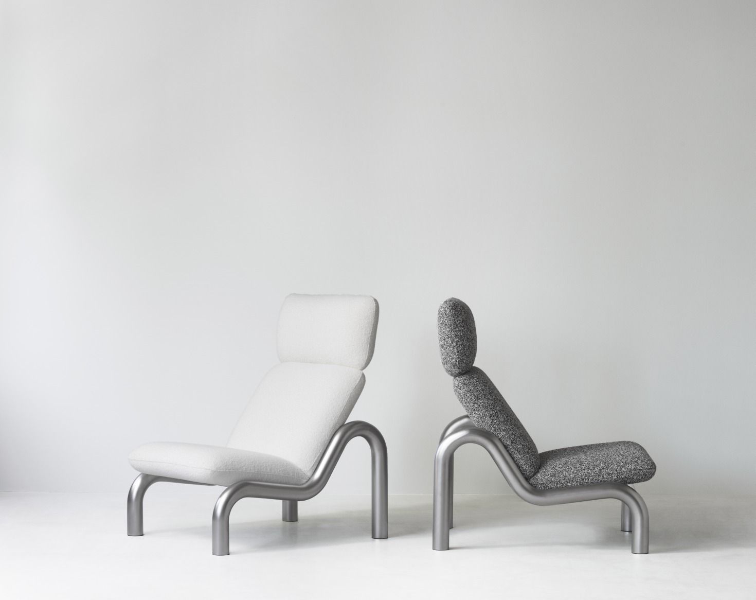 Zwei Tube Lounge Sessel von Normann Copenhagen in Weiß und Grau vor weißem Hintergrund.