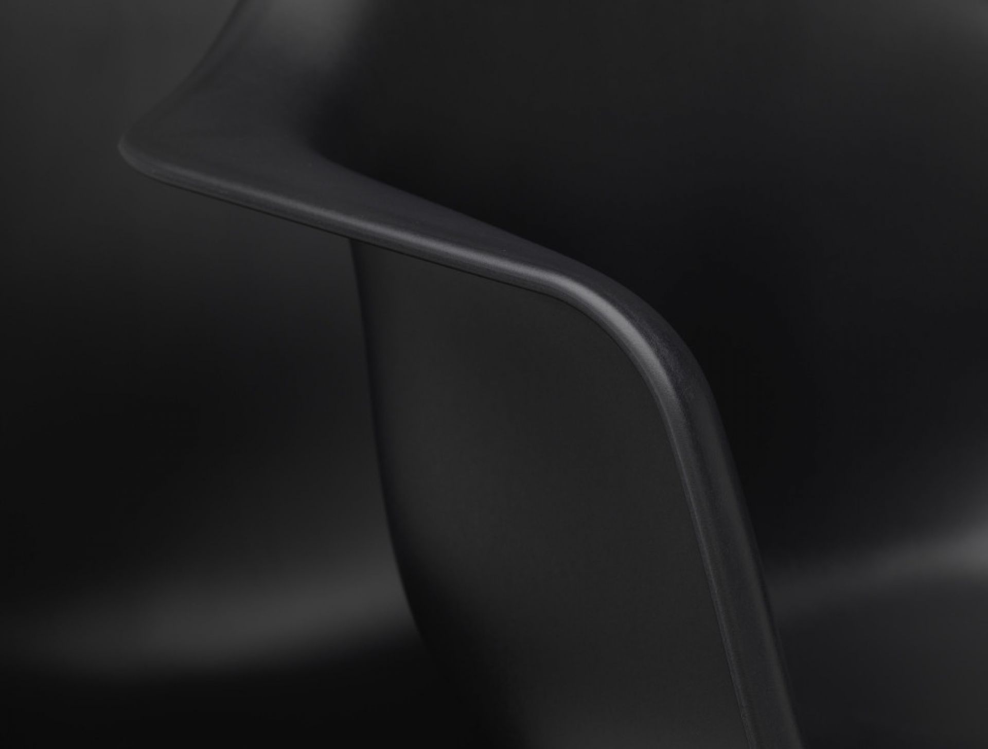 Detailaufnahme der Armlehne eines schwarzen Eames Plastic Arm Chair PACC Stuhls von Vitra.