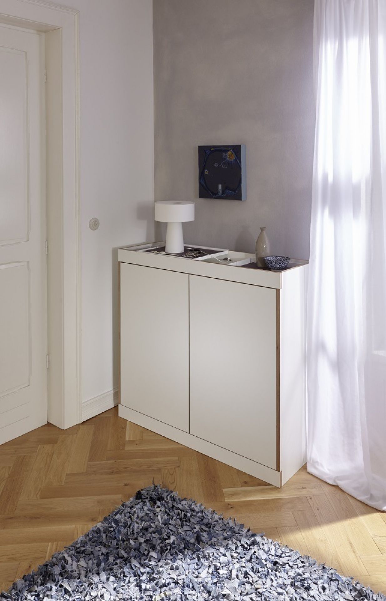 Weiße Flai Kommode von Müller Möbelwerkstätten im modernen Wohnzimmer mit Teppich und Dekoration.