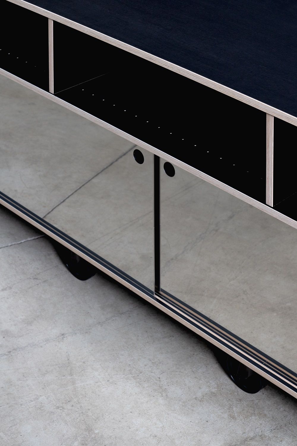 Detailaufnahme von Rockboard Sideboard von Nils Holger Moormann mit Spiegelfront und schwarzen Elementen, modernes Möbeldesign.