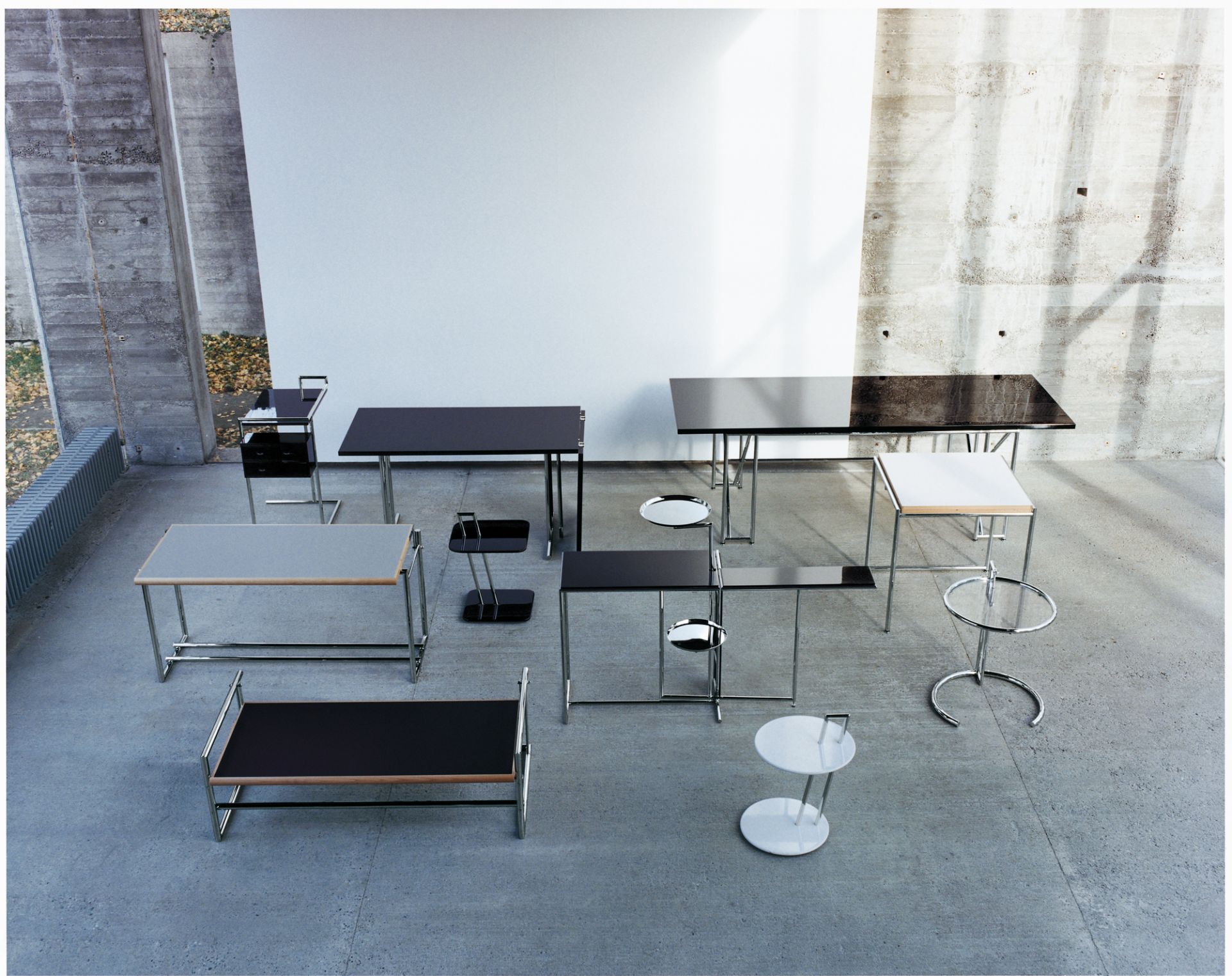 Verschiedene ClassiCon Beistelltische, darunter der Adjustable Table E1027, aus unterschiedlichen Perspektiven in einem Raum.