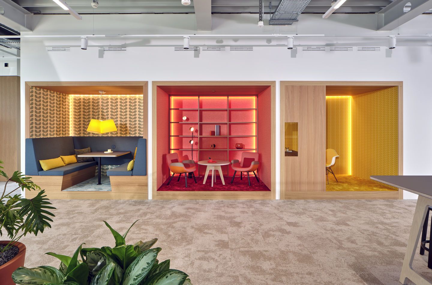 Büro-Lounge mit drei abgetrennten Bereichen, ausgestattet mit Eames Plastic Arm Chairs und modernen Möbeln von Vitra.