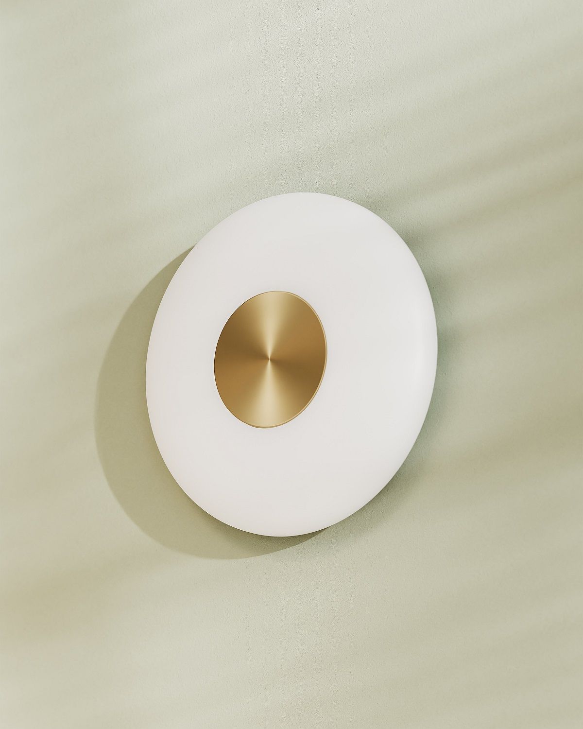 Glint Glass Wandleuchte: Runde, moderne Wandlampe mit Opalglas und goldfarbenem Detail an grüner Wand.