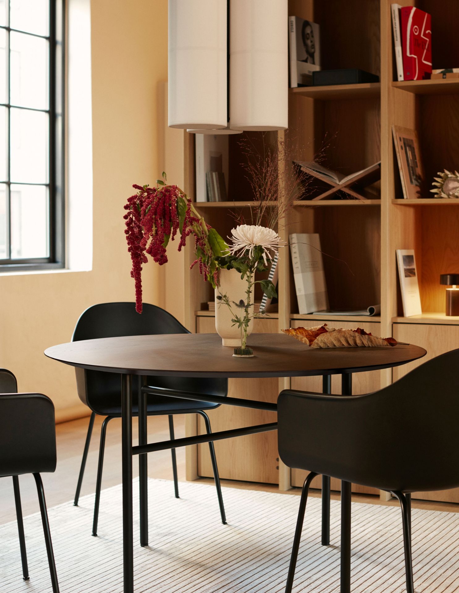 Esszimmer mit Hashira Pendelleuchten Cluster, runder Tisch und schwarzen Stühlen. Moderne Innenarchitektur.