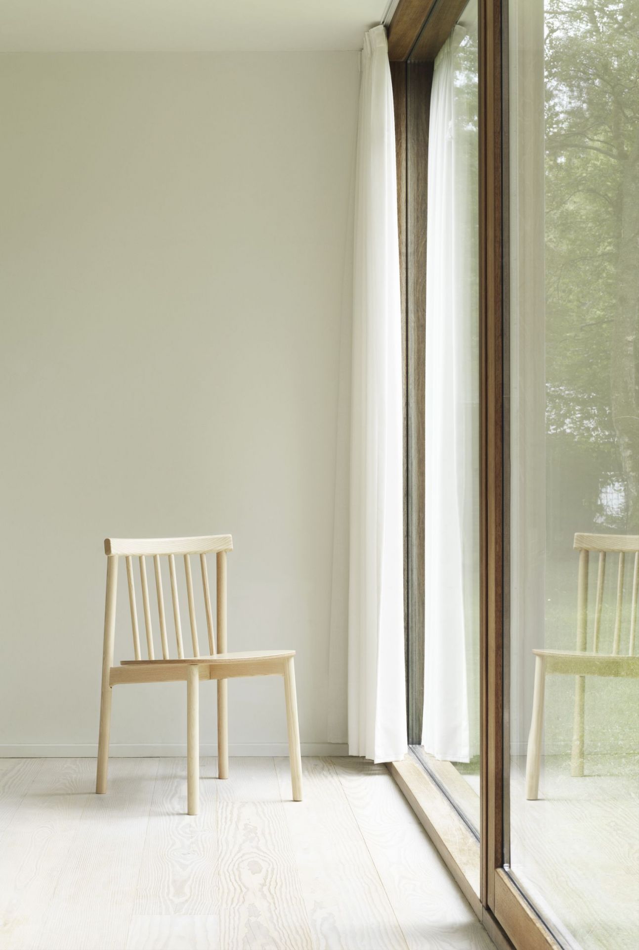 Pind Chair Stuhl von Normann Copenhagen aus hellem Holz vor Fenster mit Vorhang.