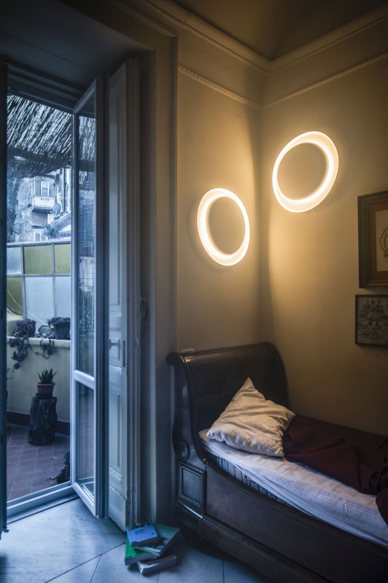Zwei runde Bahia Mini Wandleuchten von Foscarini an der Wand über einem antiken Bett.