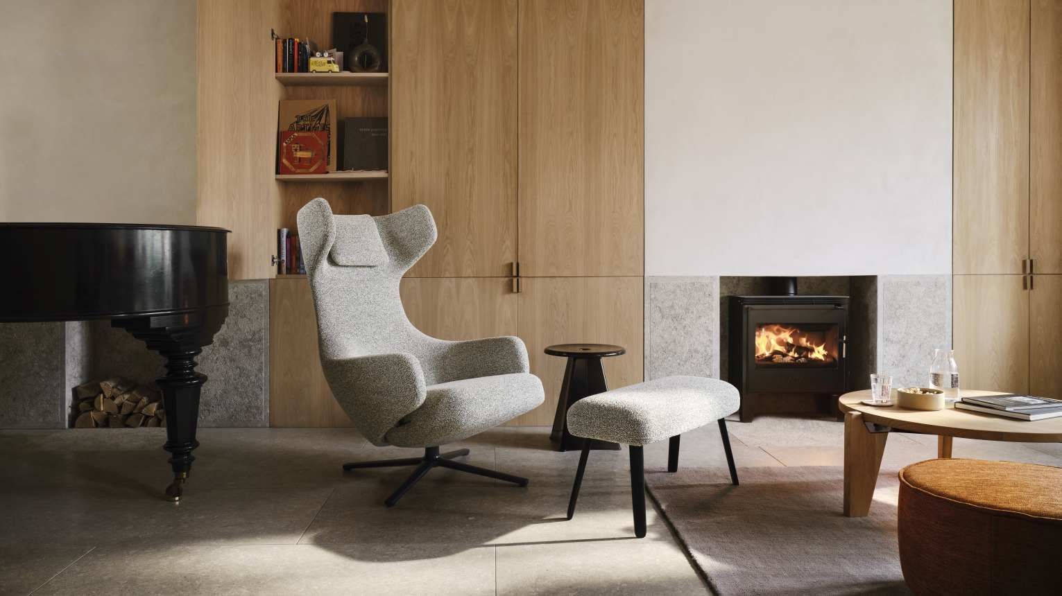 Grand Repos Sessel mit Ottoman von Vitra in Kiesel Melange vor Kamin und Klavier.