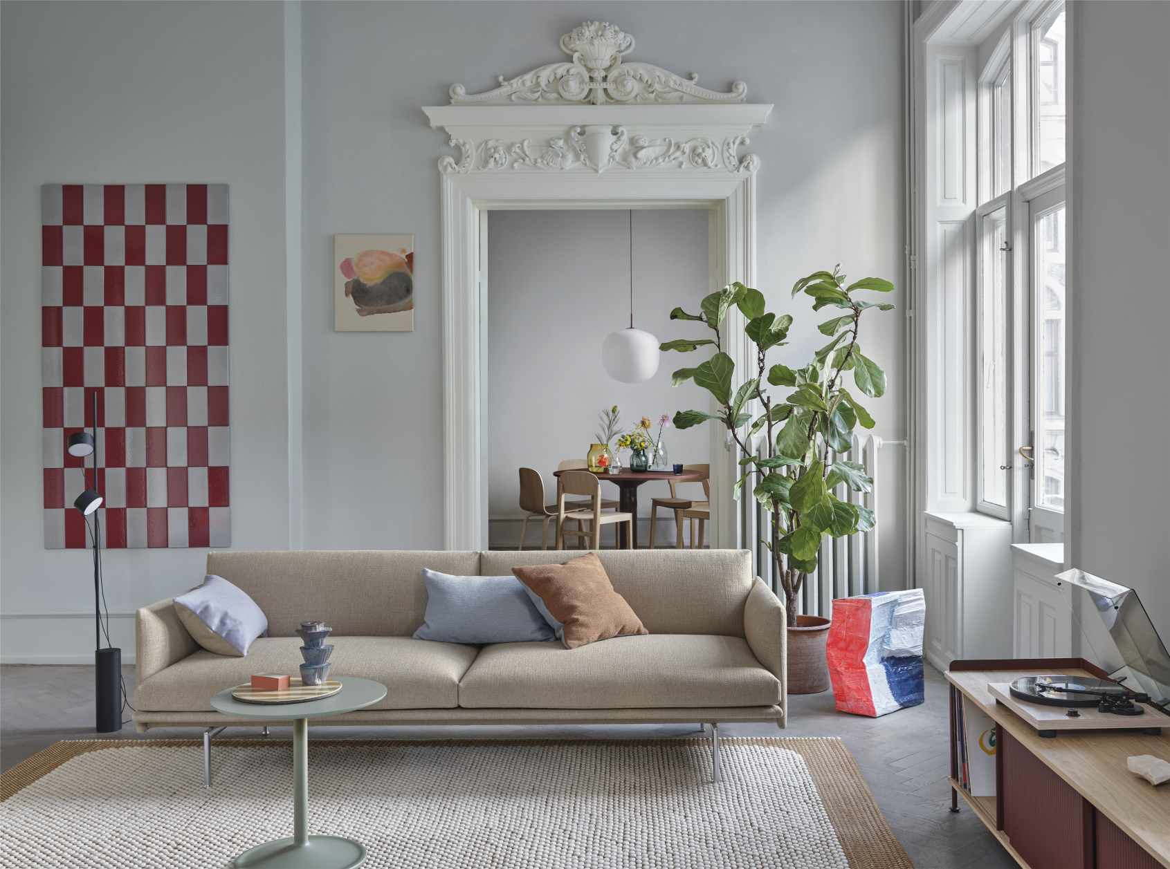 Beige Couch mit Muuto Mingle Kissen in Blau und Braun im hellen Wohnzimmer mit Designermöbeln.