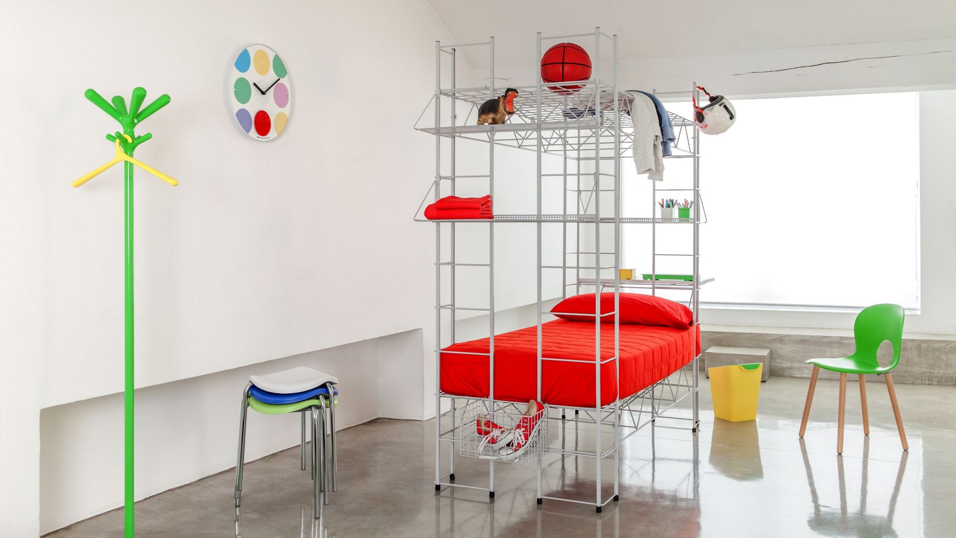 Pop Kleiderständer von Rexite im Kinderzimmer: Metallgestell mit Ablagen, rotes Bett, bunte Akzente.