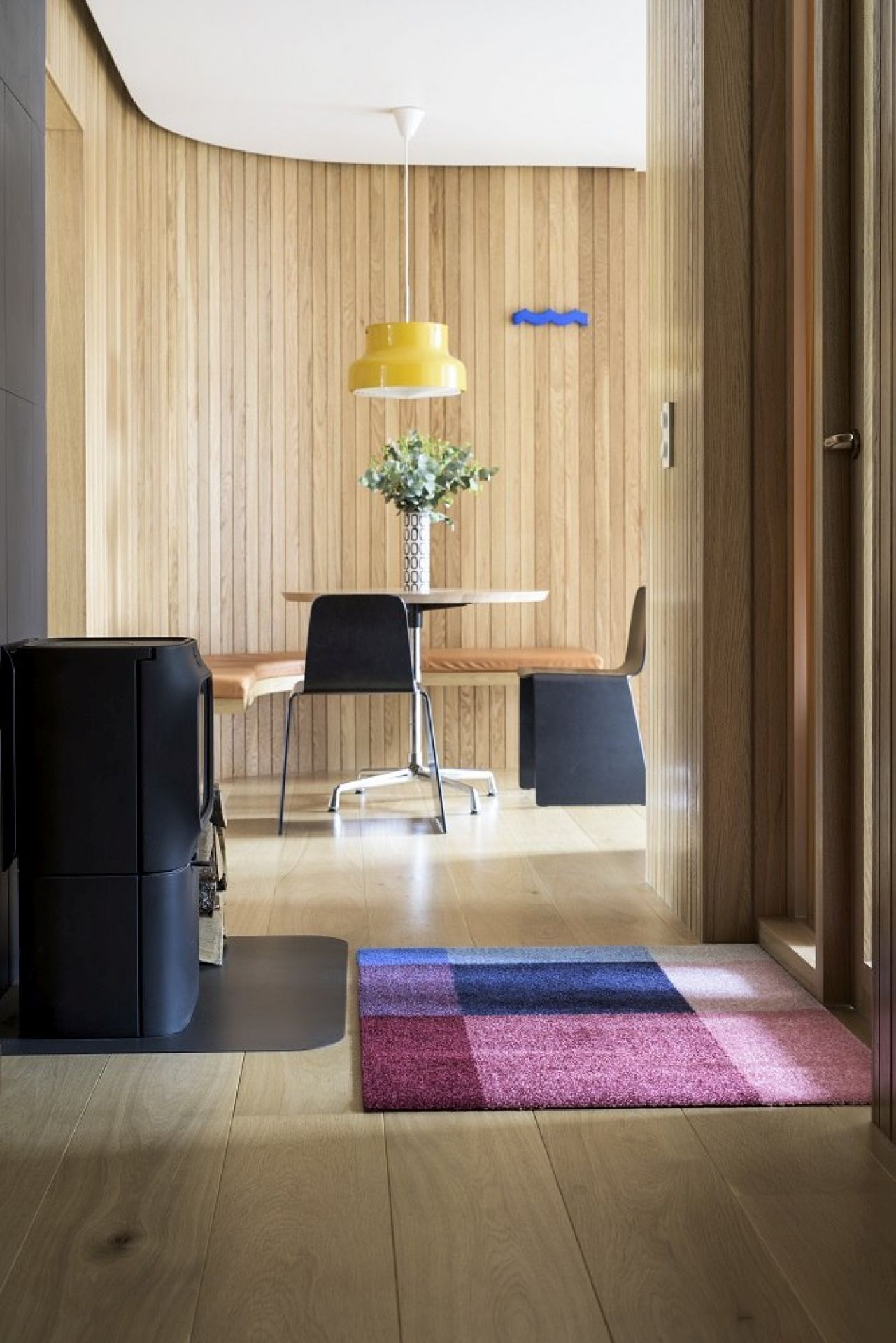 Detailaufnahme der Heymat Fußmatte "Mix" in einem modern eingerichteten Eingangsbereich mit Holzboden und Kamin.