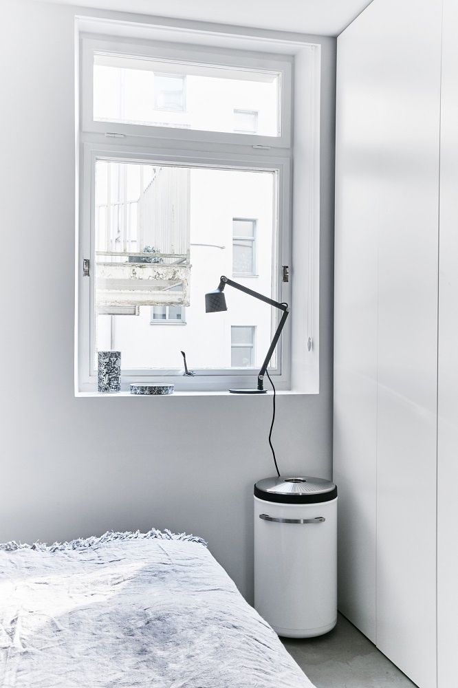 Weißer Vipp Wäschekorb im Schlafzimmer, neben Bett und Fenster mit Lampe.
