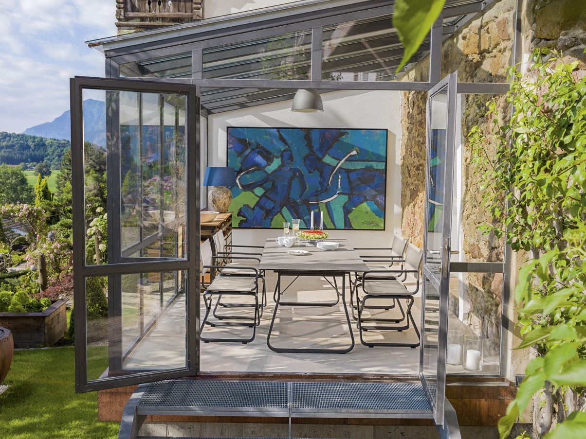 Ahoi Tisch von Weishäupl im Außenbereich, grauer Gartentisch mit Stühlen in Glashaus.