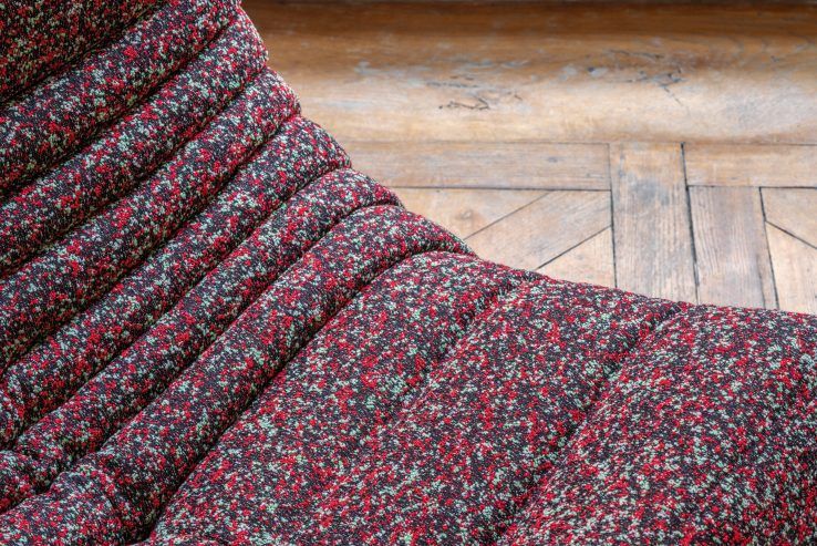 Detailaufnahme des roten Togo Sessel ligne roset mit Cordbezug und Holzboden im Hintergrund.
