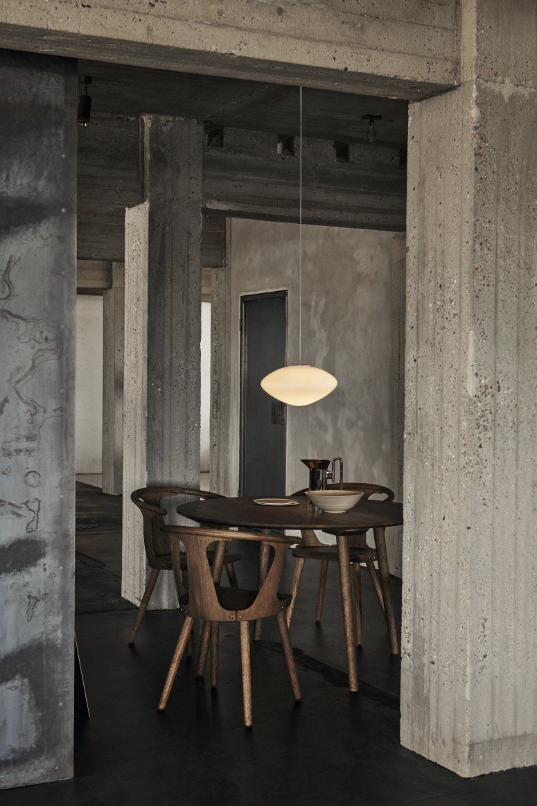 AndTradition Mist Pendelleuchte aus Opalglas über Esstisch mit Holzstühlen in modernem Interieur.