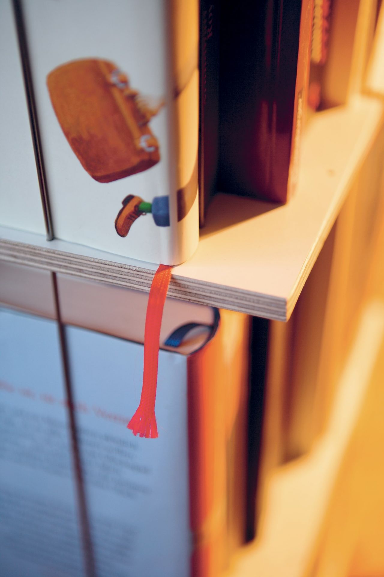 Detailaufnahme eines Buchstaplers von Nils Holger Moormann, gefüllt mit Büchern und einem roten Lesezeichen.