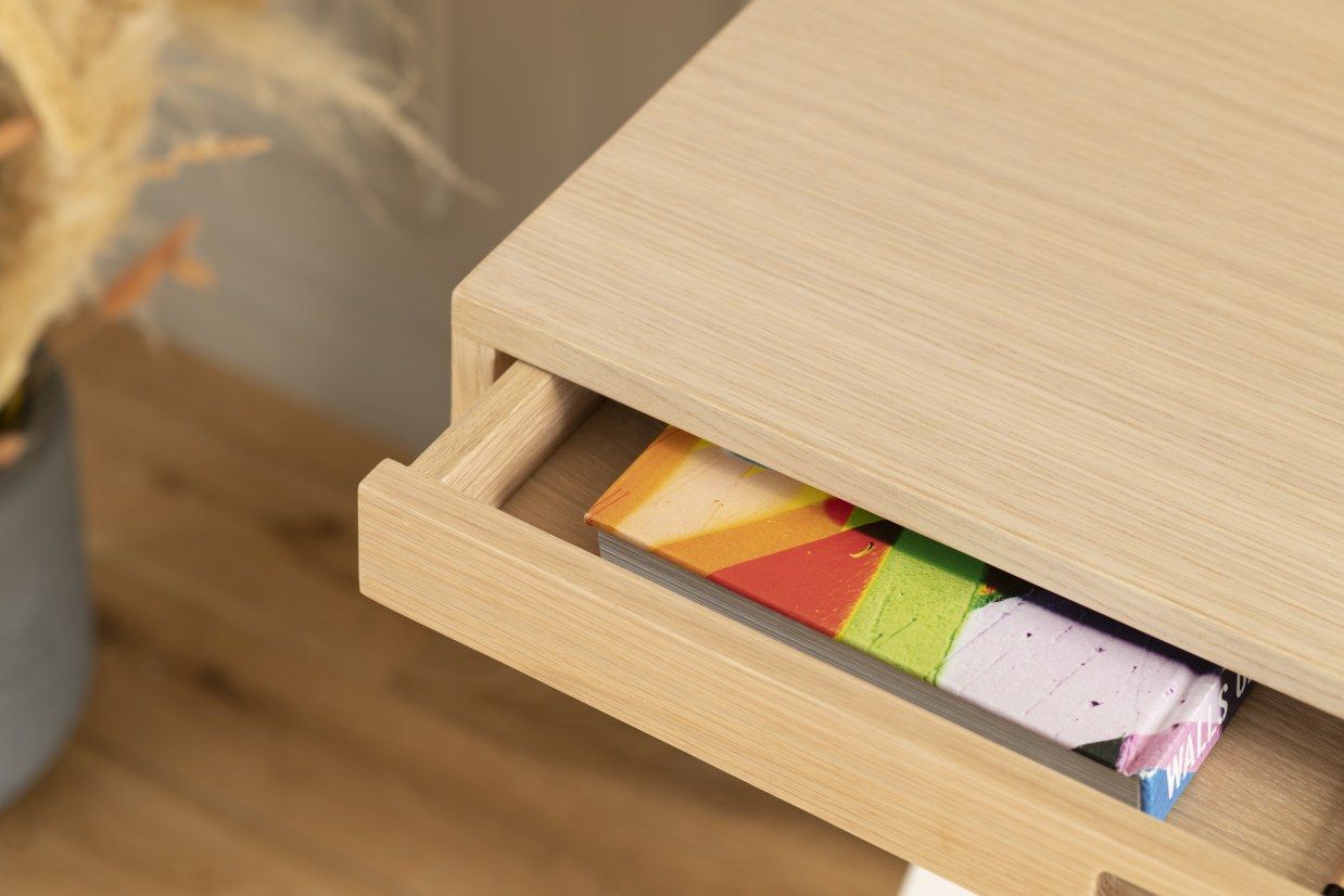 Detailaufnahme des Hyppolite Sekretärs Hartô mit offener Schublade und bunten Büchern, helle Holzoptik.