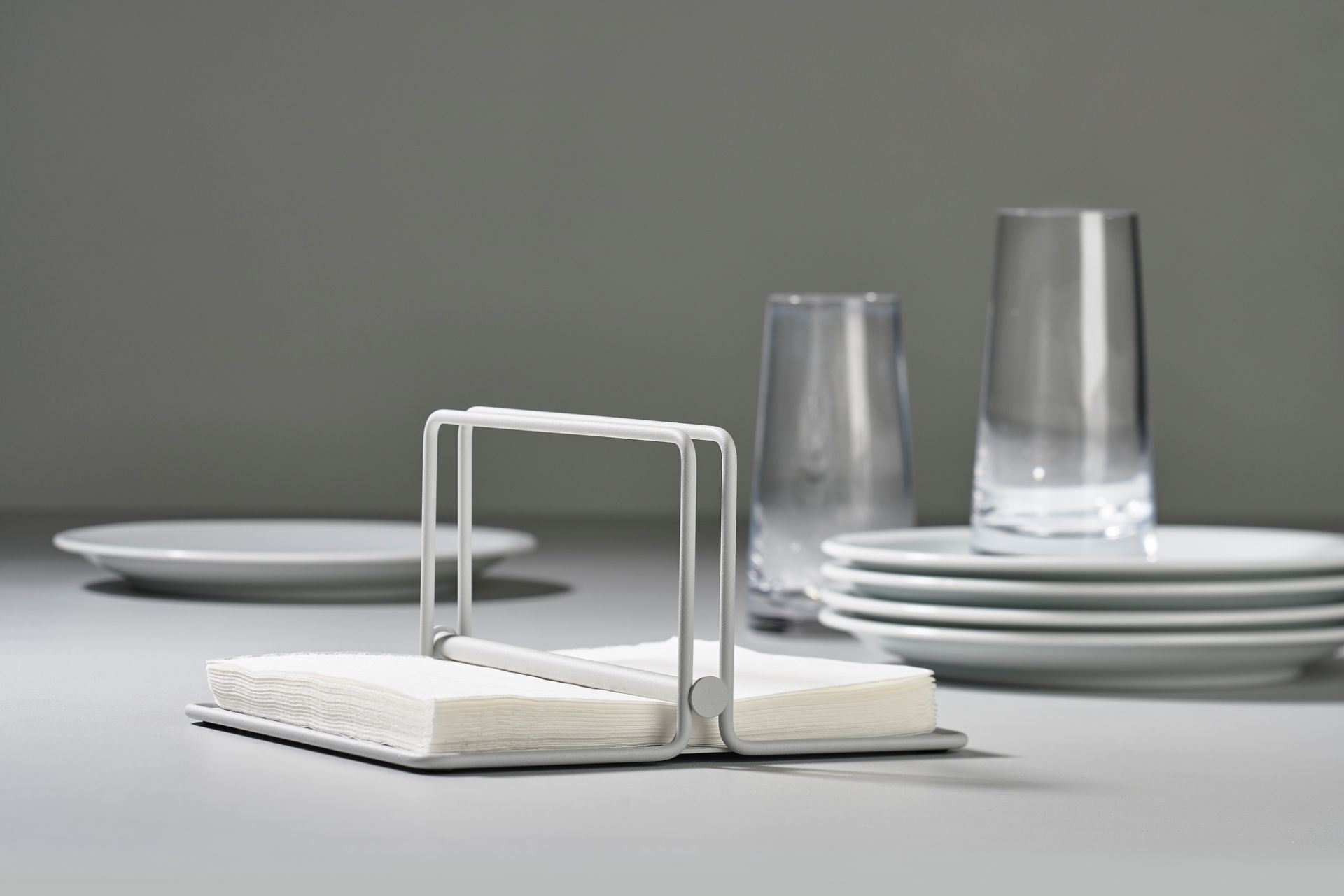 Weißer Serviettenhalter "Singles" von Zone Denmark mit Servietten auf einem Tisch mit Geschirr.