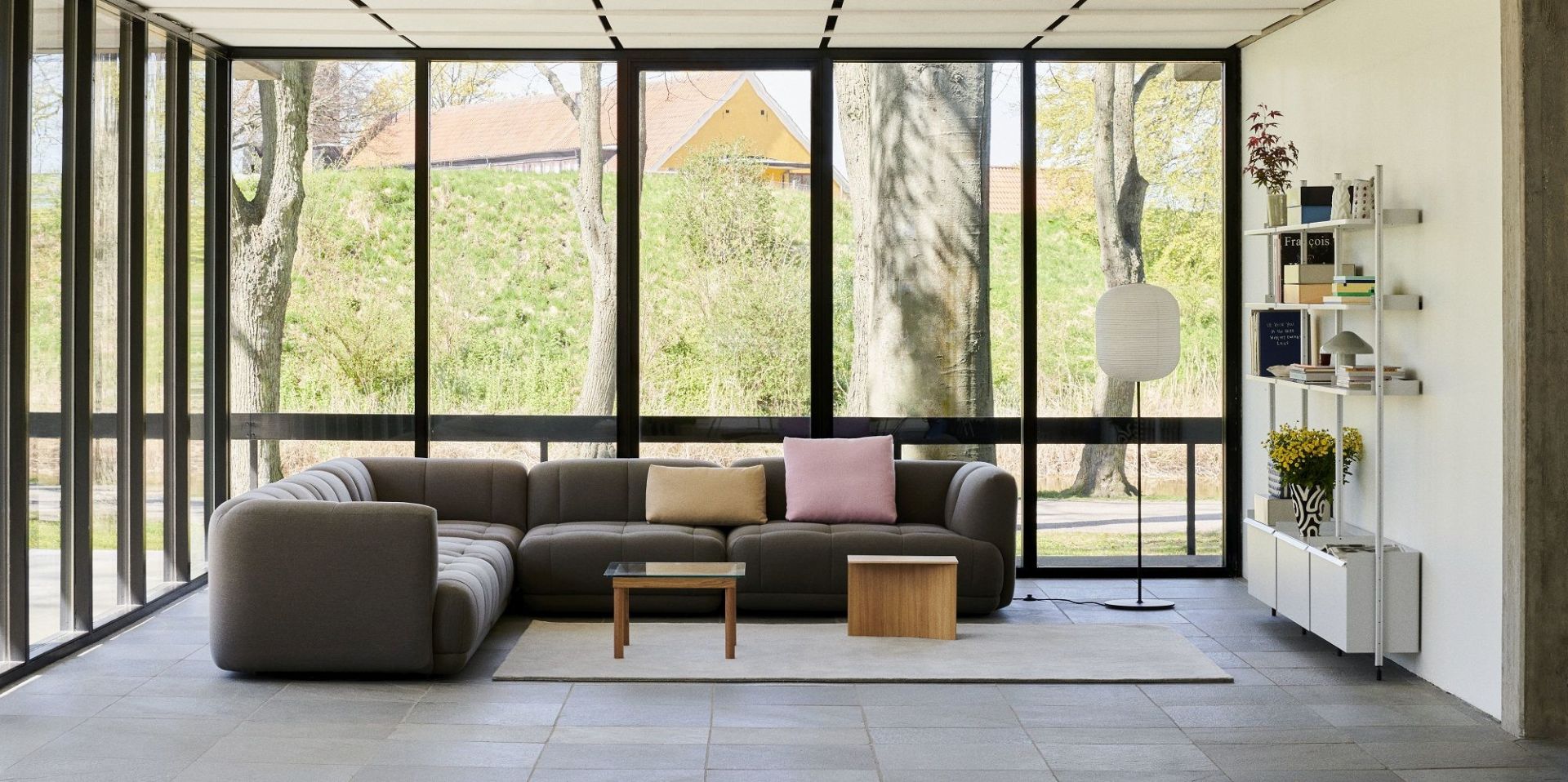 Helles Wohnzimmer mit großem Fenster und weißem Hay Pier System Regal mit drei Säulen.