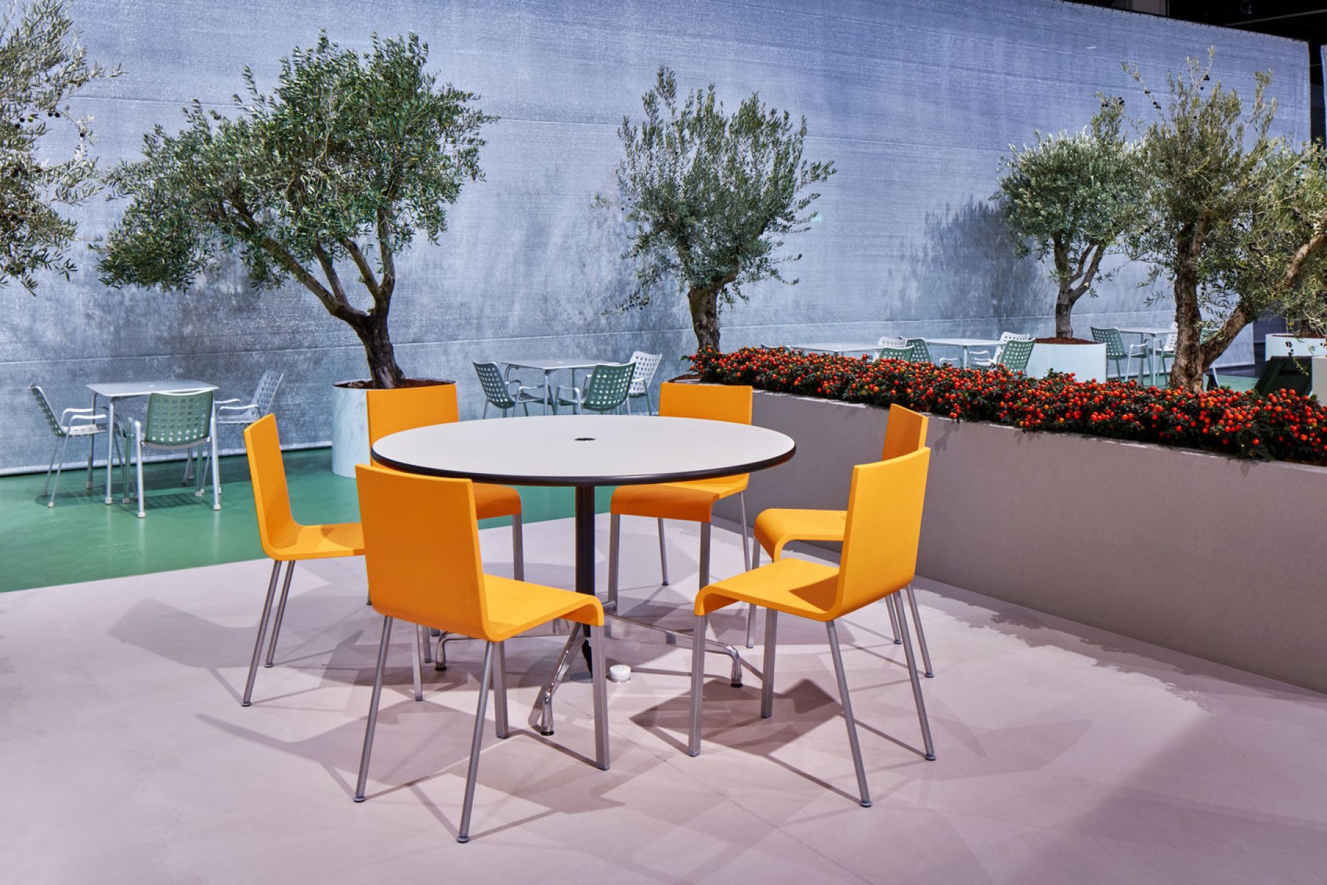.03 Stuhl von Vitra in Orange um einen runden Tisch im Außenbereich.