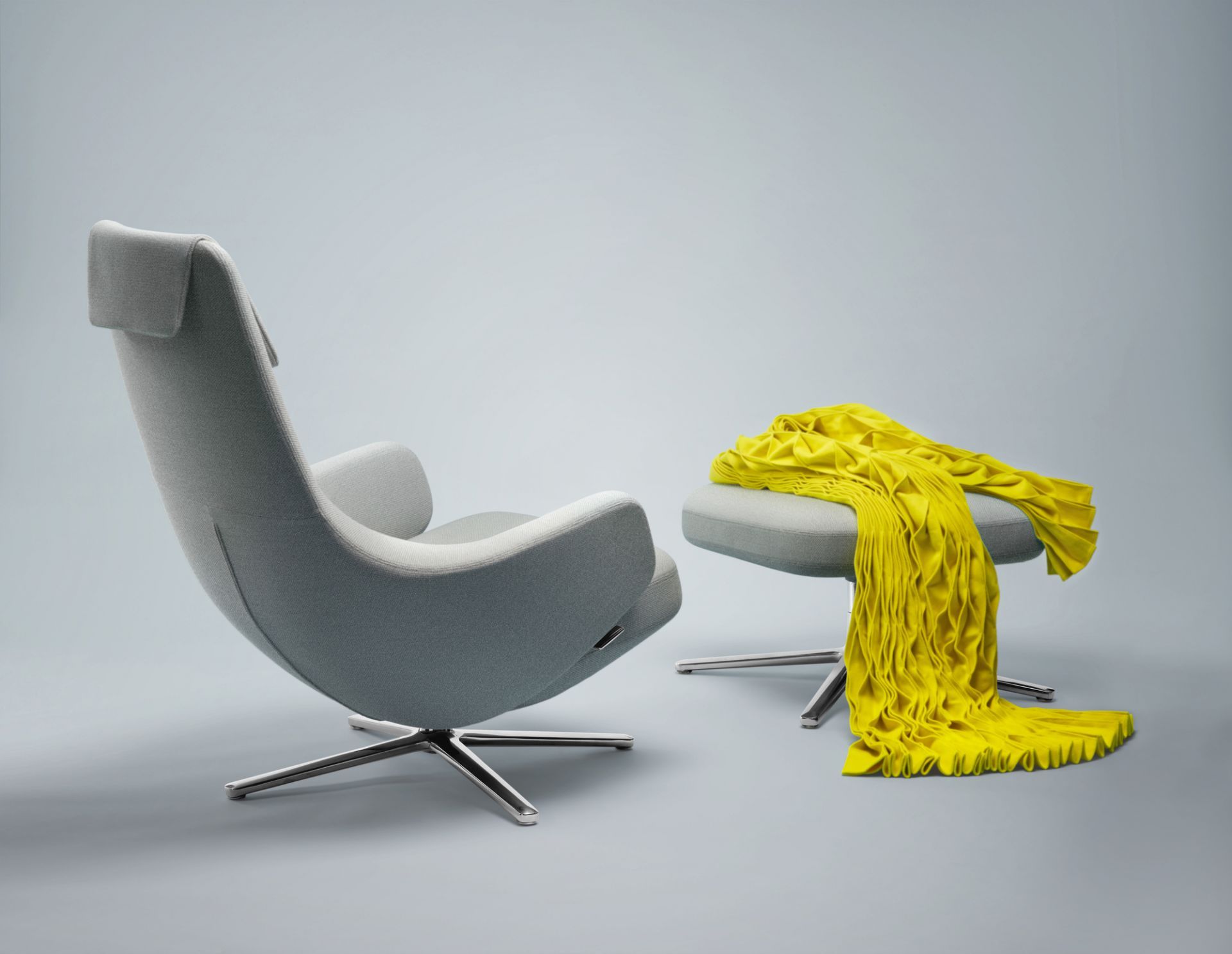 Grauer Repos Sessel von Vitra mit Ottoman und gelber Decke, modernes Design für Wohnzimmer.