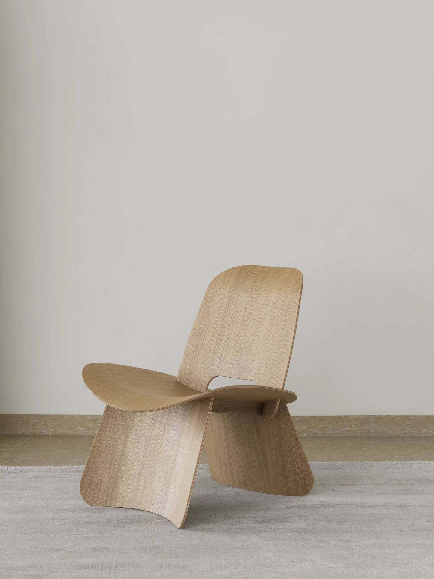 Nagomi Chair von Blomus: Moderner Holzstuhl mit minimalistischem Design und skulpturaler Form auf Teppich.