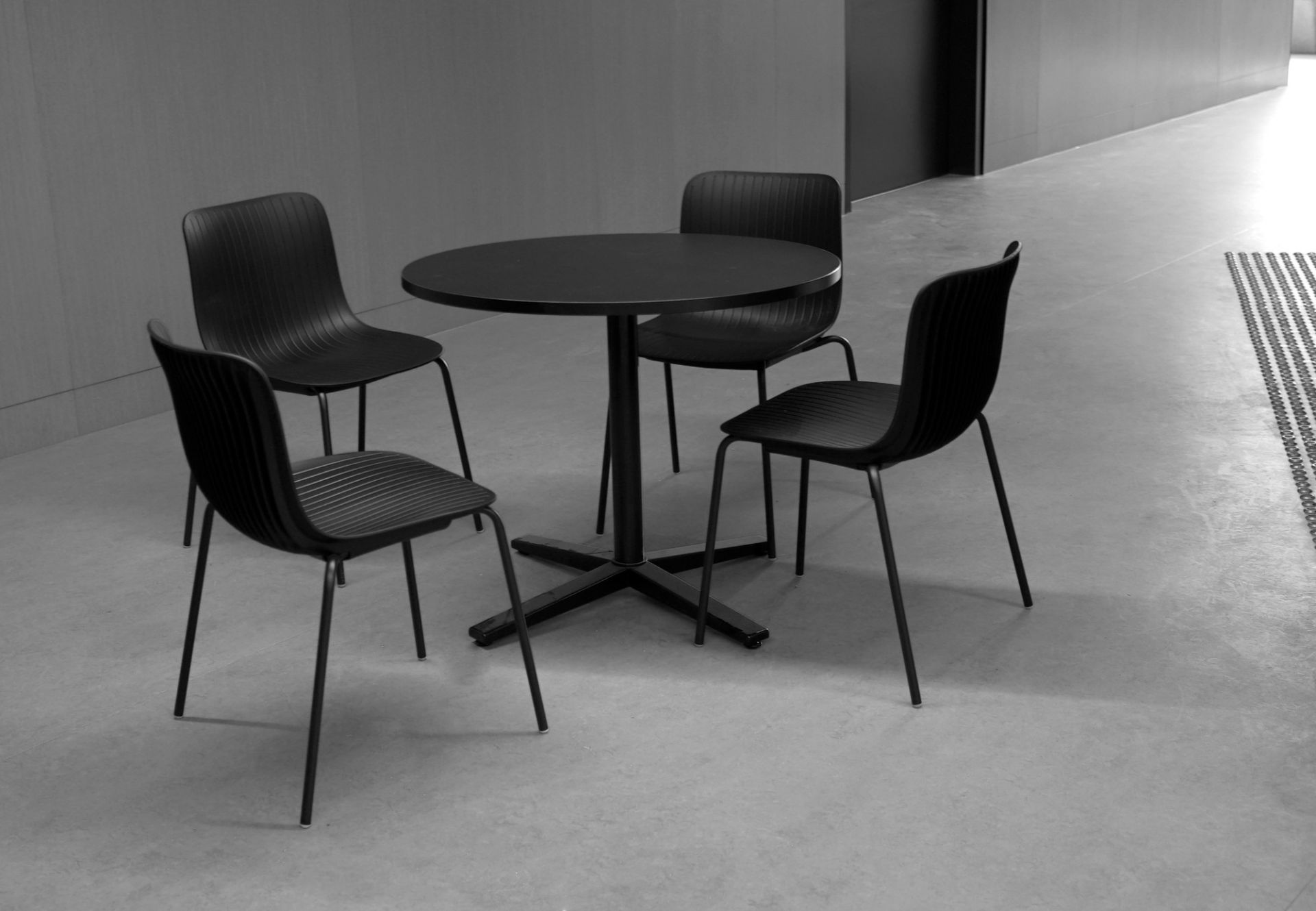 Vier schwarze Dragonfly Stühle um einen runden Tisch. Stapelbare Design Stühle für Büro und Zuhause.