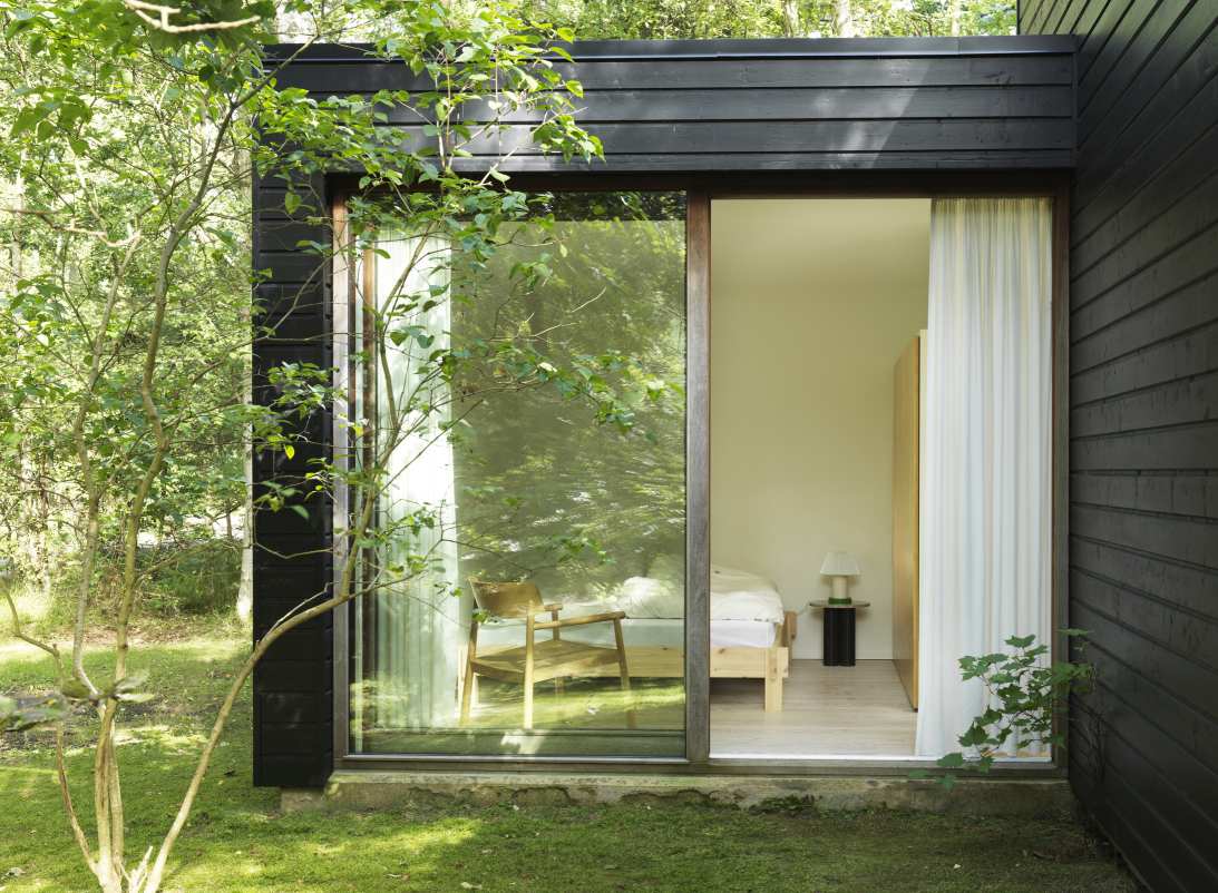 Ansicht eines modernen Schlafzimmers mit Normann Copenhagen Beistelltisch, gesehen durch ein großes Fenster.