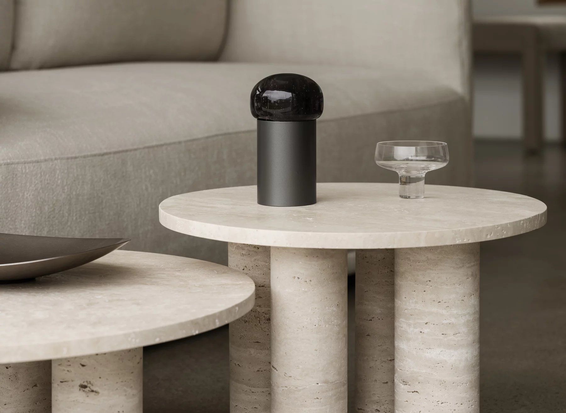 Blomus Volos Couchtisch rund, beige Travertin mit drei zylindrischen Beinen, modernes Wohnzimmer-Interieur.