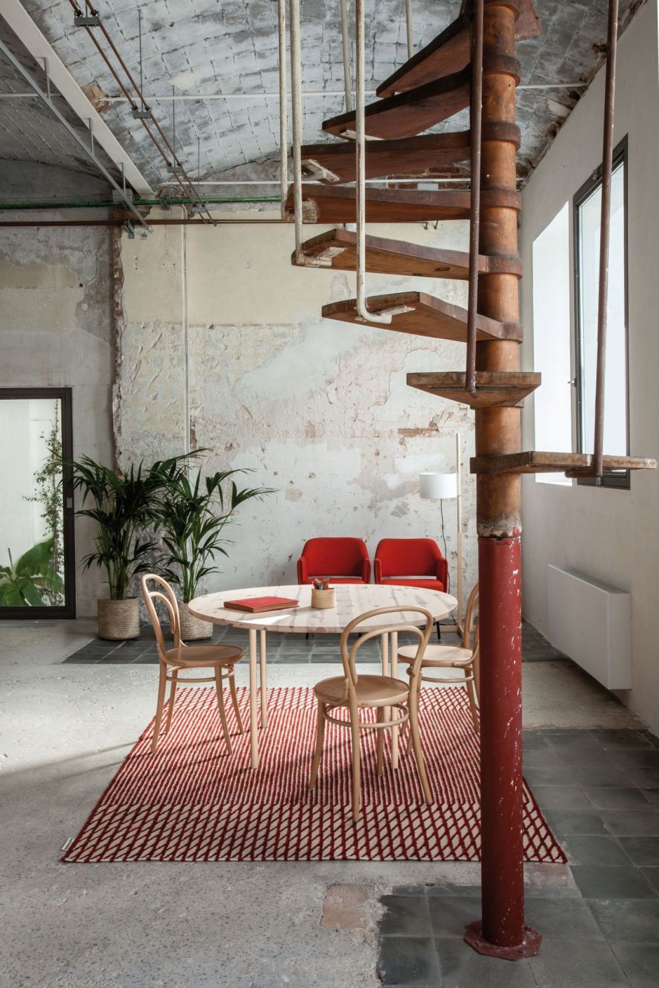 Roter Nanimarquina Blur Teppich in Loft mit Tisch, Stühlen und Wendeltreppe.