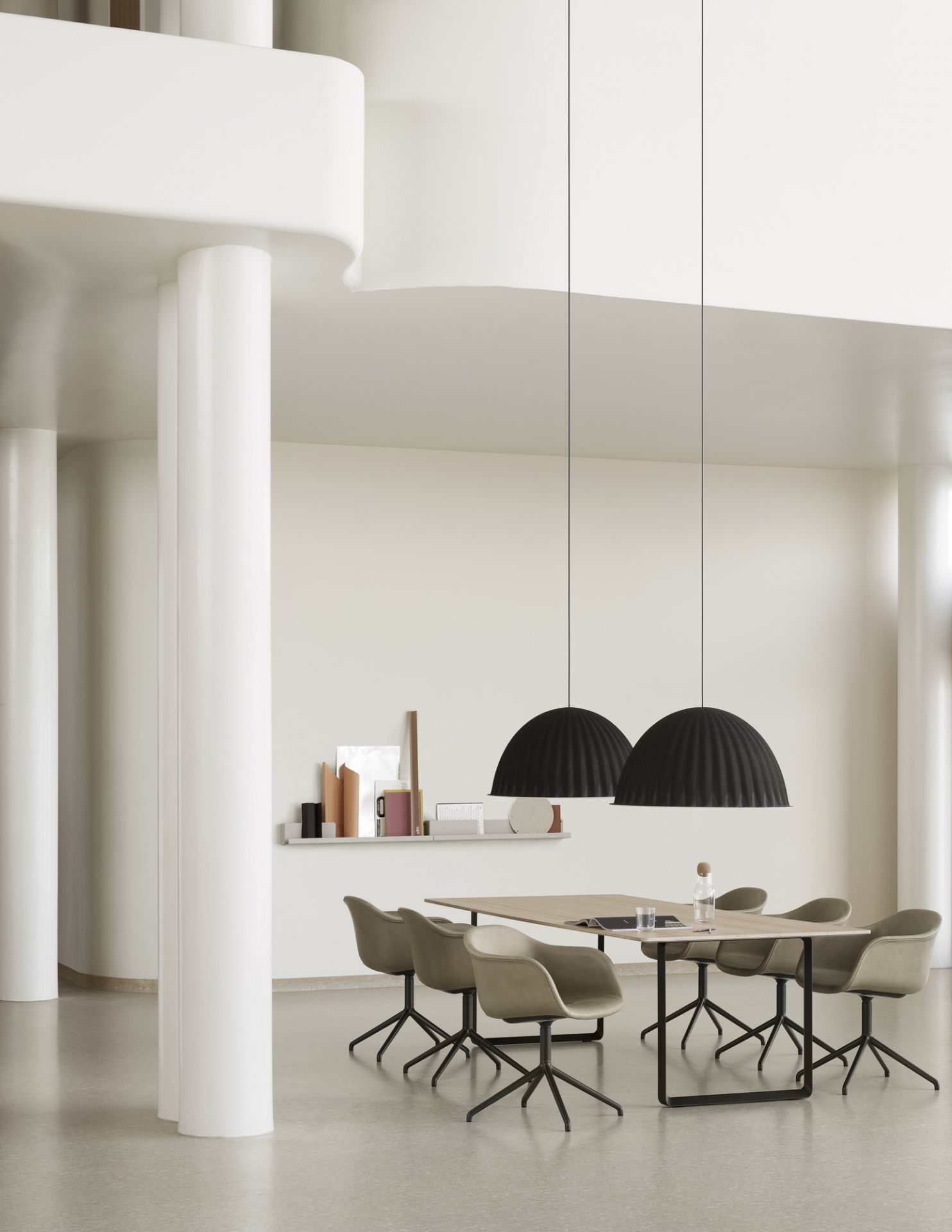 Helle Raumszene mit Esstisch, Stühlen und zwei schwarzen Under The Bell Pendelleuchten von Muuto.