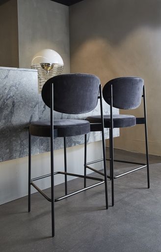 Zwei graue Verpan Series 430 Barhocker mit schwarzem Gestell und Fußstütze vor einer Küchentheke.