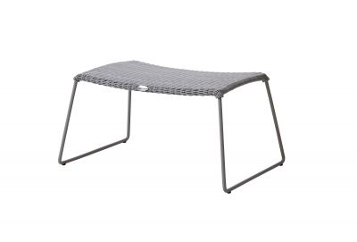 Grauer Cane-Line Hocker für den Außenbereich mit geflochtener Sitzfläche und Metallgestell.