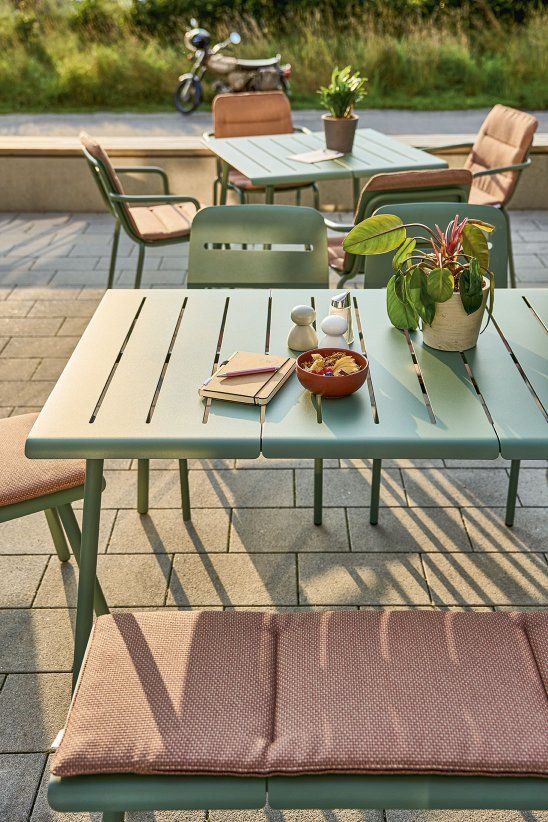 Weishäupl Vapio Stuhl und Gartentisch Set in Grün mit Kissen und Dekoration im Freien.